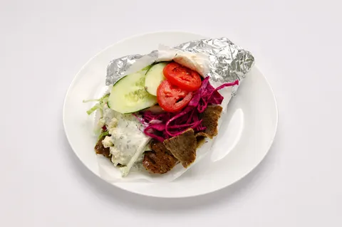 Döner kebab with shaved meat, vegetables, feta, and tzatziki